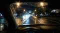 Nachtfahrt scene, low light, viewed from inside a car with oncoming headlights and city lights.
